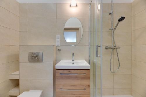 a bathroom with a sink and a shower with a mirror at Laguna Centrum by Grand Apartments in Sopot