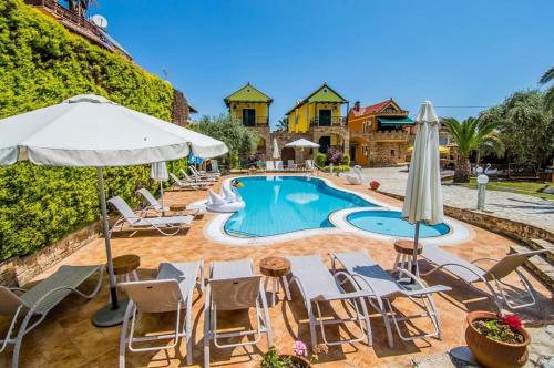 a pool with chairs and umbrellas next to a house at Kastro Stone House in Skala Potamias