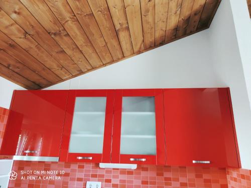a kitchen with red cabinets and a wooden ceiling at Apartment M&M in Primošten