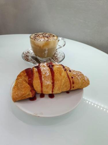 a cup of coffee and a croissant on a table at Le stanze di Dalia in Crotone