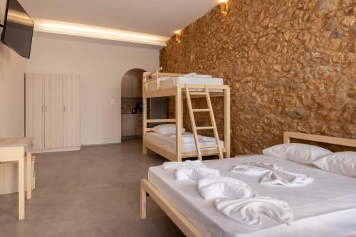 1 dormitorio con 2 literas y pared de piedra en MARKOS LUXURY APARTMENTS, en Koroni