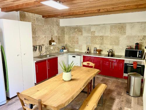 a kitchen with red cabinets and a wooden table at Maison les pieds dans l'eau in Villefort