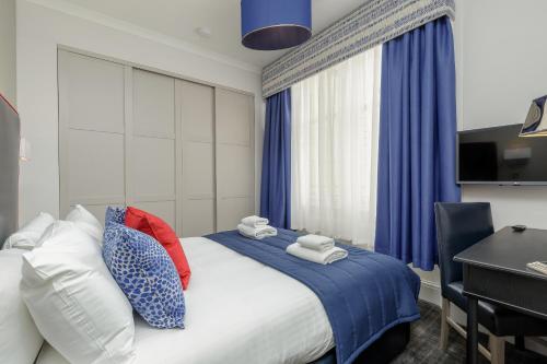 a bedroom with a bed with blue curtains and a desk at Destiny Scotland - Princes Street Residence in Edinburgh