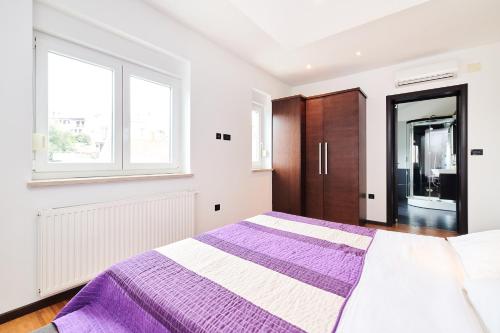 a bedroom with a purple and white bed and a window at Ribarska Koliba - Stella Adria Villa in Pula