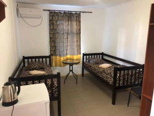 two beds in a room with a table and a window at Shaarei Zion in Umanʼ