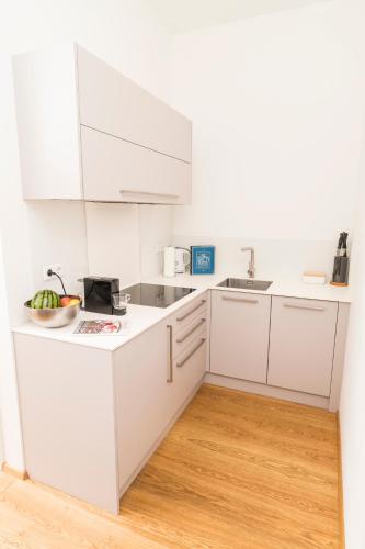 a white kitchen with white cabinets and a wooden floor at Mint@Naschmarkt Premium Apartments in Vienna
