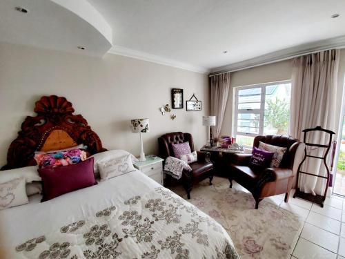 a bedroom with a bed and a desk and chairs at Gordon's Beach Lodge in Gordonʼs Bay