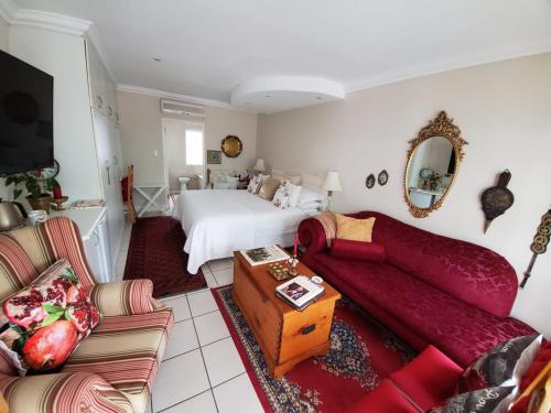 a bedroom with a bed and a living room with a couch at Gordon's Beach Lodge in Gordonʼs Bay