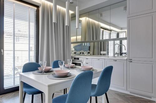 a dining room with a white table and blue chairs at Grand Apartments · Okrzei Residence in Sopot