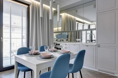 jadalnia z białym stołem i niebieskimi krzesłami w obiekcie Grand Apartments · Okrzei Residence w mieście Sopot