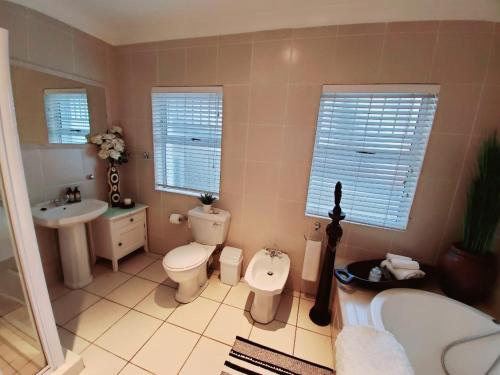 a bathroom with a tub and a toilet and a sink at Gordon's Beach Lodge in Gordonʼs Bay
