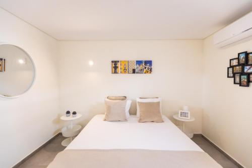 a white bedroom with a bed and a mirror at Ambassador Private Pool Suites in Lisbon