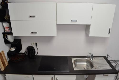 cocina con fregadero y armarios blancos en Apartamenty u Majki 2, en Frydman