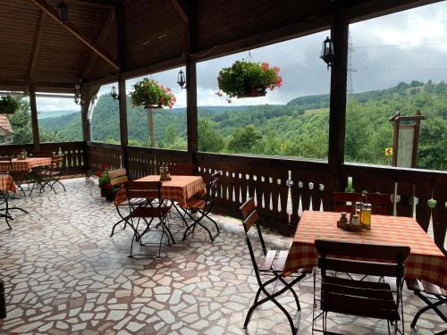 a restaurant with tables and chairs and a view of the mountains at Csíki Határ Fogadó/ Hanul Hotarul Ciucului in Bixad