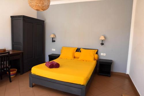 a bedroom with a bed with yellow sheets and yellow pillows at Hotel Victoria in Diego Suarez