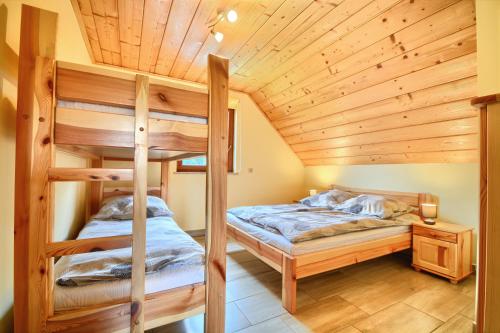 two bunk beds in a room with a wooden ceiling at SŁONECZNE DOMKI in Istebna