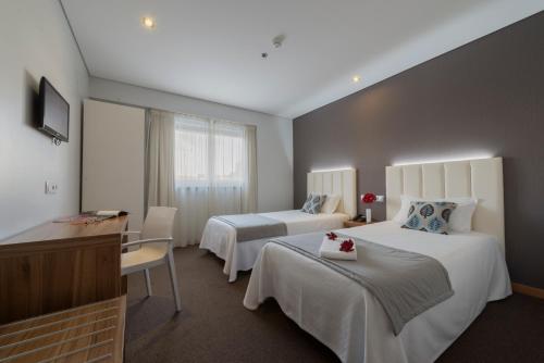 ファティマにあるHotel Azinheiraのベッド2台とデスクが備わるホテルルームです。