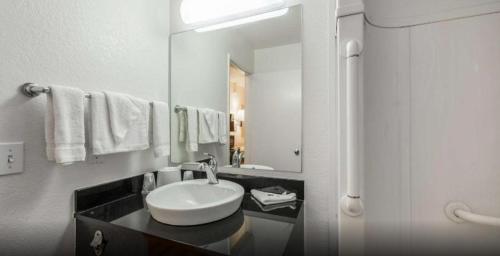 a white bathroom with a sink and a mirror at Studio 6 Wichita, KS - Airport in Wichita