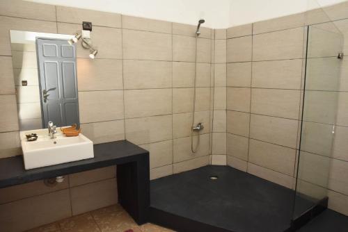 a bathroom with a sink and a shower with a mirror at Hotel Victoria in Diego Suarez