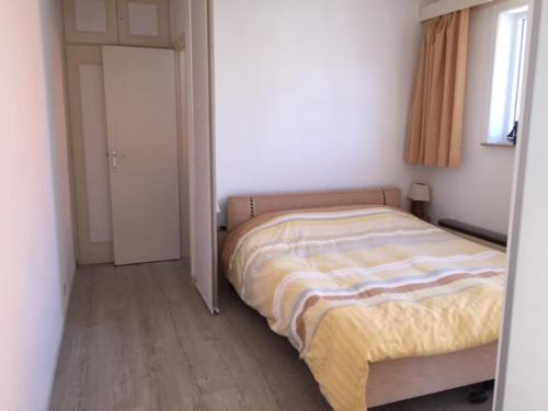 um pequeno quarto com uma cama e uma janela em Gezellig appartement voor het gezin em Middelkerke