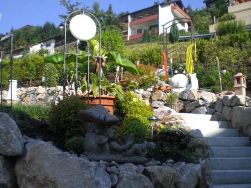 a garden with a stone statue in the middle of some rocks at Gästehaus und Ferienwohnung Bächle in Bad Peterstal