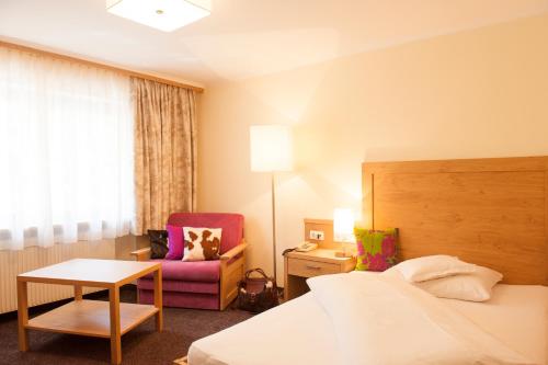 a hotel room with a bed and a chair at Pension Iris in Lech am Arlberg
