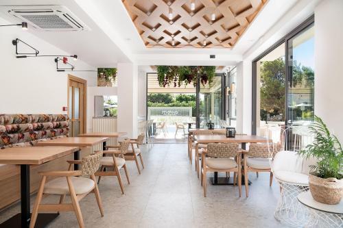 a restaurant with wooden tables and chairs and windows at Mossa Well Being Hotel - Heated pool in Kato Daratso
