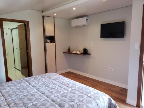 Schlafzimmer mit einem Bett und einem Flachbild-TV in der Unterkunft Hospedaria Felder in Treze Tílias