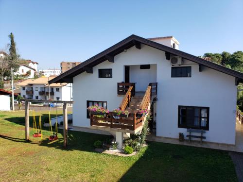 a white house with a porch and a balcony at Hospedaria Felder in Treze Tílias