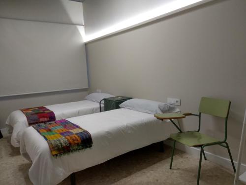 pokój z 2 łóżkami i krzesłem w obiekcie Acolá Rooms w mieście Pontevedra