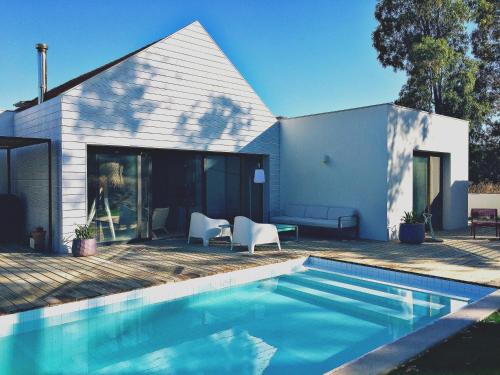 a swimming pool in front of a house at Manos 114 in Comporta