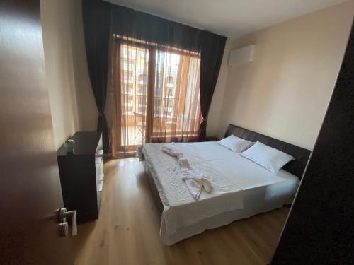 sypialnia z łóżkiem z białą pościelą i oknem w obiekcie Elegantz Apartments 1 w Warnie