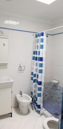 baño con cortina de ducha azul y blanco y aseo en Viviendas Las Vistas, en Puerto del Carmen