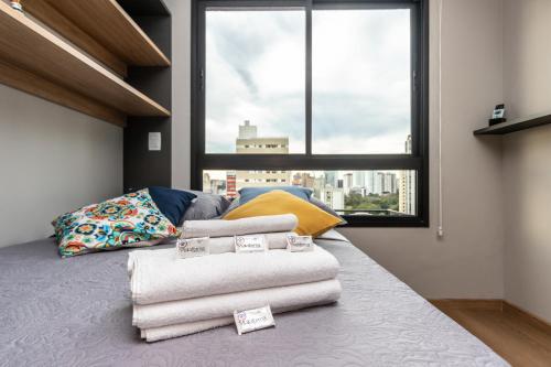 a bedroom with towels on a bed with a window at Vista Passeio Público - AYN027 in Curitiba