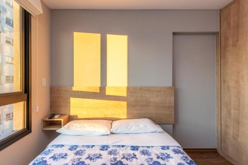 a bedroom with a bed and a yellow painting on the wall at Studio Serra do Mar - Central - AYN029 in Curitiba