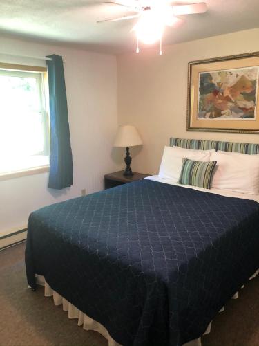 a bedroom with a bed with a blue comforter and a window at Admiral Digby Inn Restaurant and Cottages in Digby