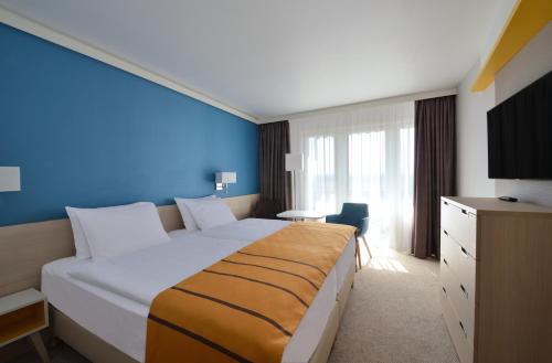 1 dormitorio con 1 cama grande y pared azul en Danubius Hotel Bük en Bük