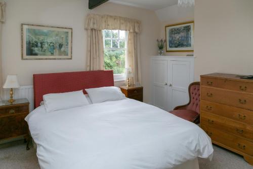 a bedroom with a large white bed and a dresser at The Garden House Grittleton in Grittleton