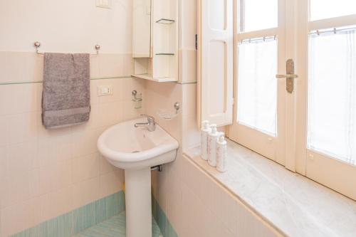 baño blanco con lavabo y ventana en Casa Gallizza con vista mare by Wonderful Italy en Cefalú