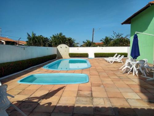 a swimming pool on a patio with chairs and an umbrella at Casinha no Sal - Tangaroa Residencial in Salinópolis