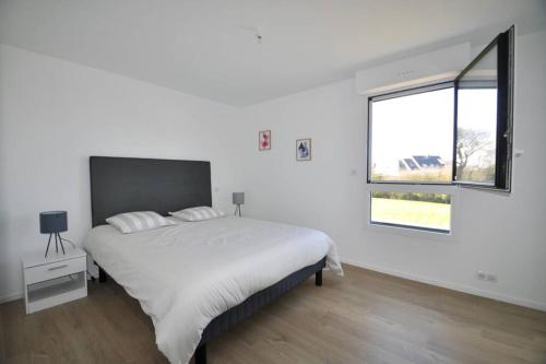 Un dormitorio blanco con una cama grande y una ventana en Villa de l'albatros Sables d'or, en Plurien
