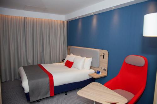 a hotel room with a bed and a red chair at Holiday Inn Express Cardiff Bay, an IHG Hotel in Cardiff