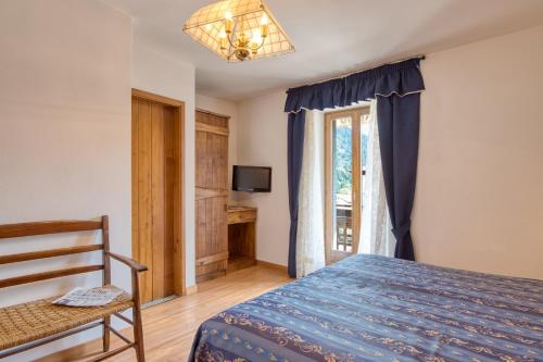 a bedroom with a bed and a window and a chair at Albergo Moleta in Spiazzo