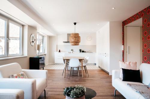 LE 19 KLEBER climatisé في كولمار: غرفة معيشة بأثاث أبيض وطاولة