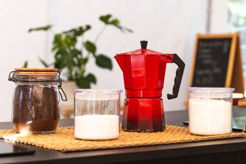 un mixeur rouge et deux récipients de lait sur une table dans l'établissement WolfCamp Surf Moliets, à Moliets-et-Maa