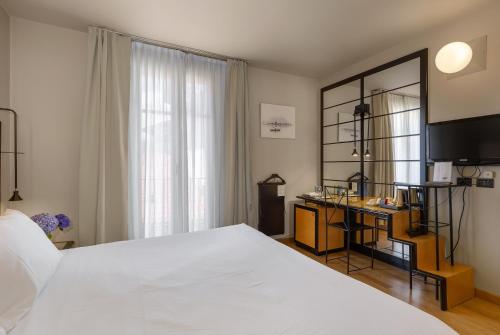 a bedroom with a large white bed and a desk at Hotel Ancora in Verbania