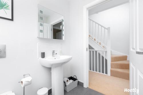 a white bathroom with a sink and a staircase at Turtle and Rabbit - Comfortable and Spacious Houses in Slough