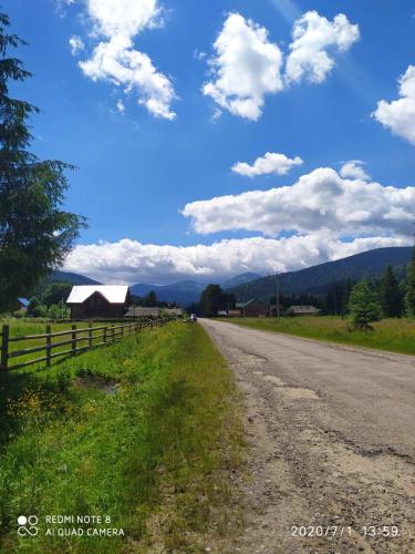 a dirt road with a fence and a house on the side at Під Явором in Vorokhta