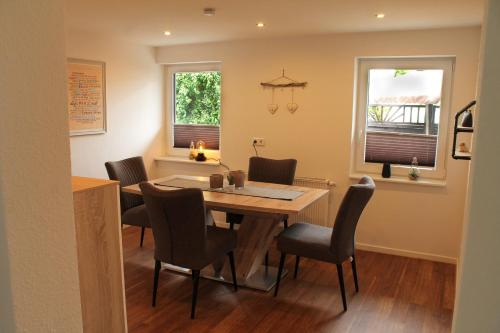 a dining room with a table and chairs and two windows at Ferienhaus Pape Gleidorf in Schmallenberg