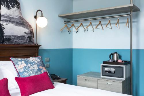 a bedroom with blue walls and a bed with red pillows at Hotel Indigo Verona - Grand Hotel Des Arts by IHG in Verona